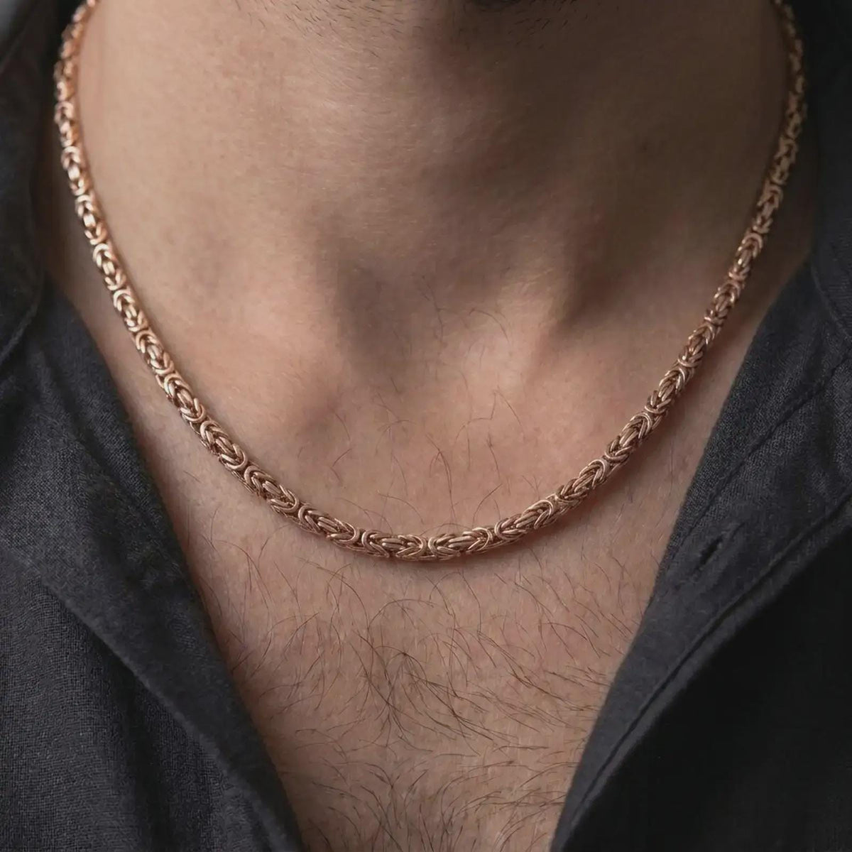 The rose gold plated 4mm square Byzantine chain necklace is worn naturally on a man’s chest, showcasing its intricate square Byzantine pattern and elegant masculine finish in a detailed lifestyle shot.