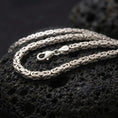 Load image into Gallery viewer, The polished silver 5mm square Byzantine chain necklace is displayed on textured black volcanic rock, highlighting the clean geometric weave, lobster clasp, and 925 silver stamp in a premium macro photograph.
