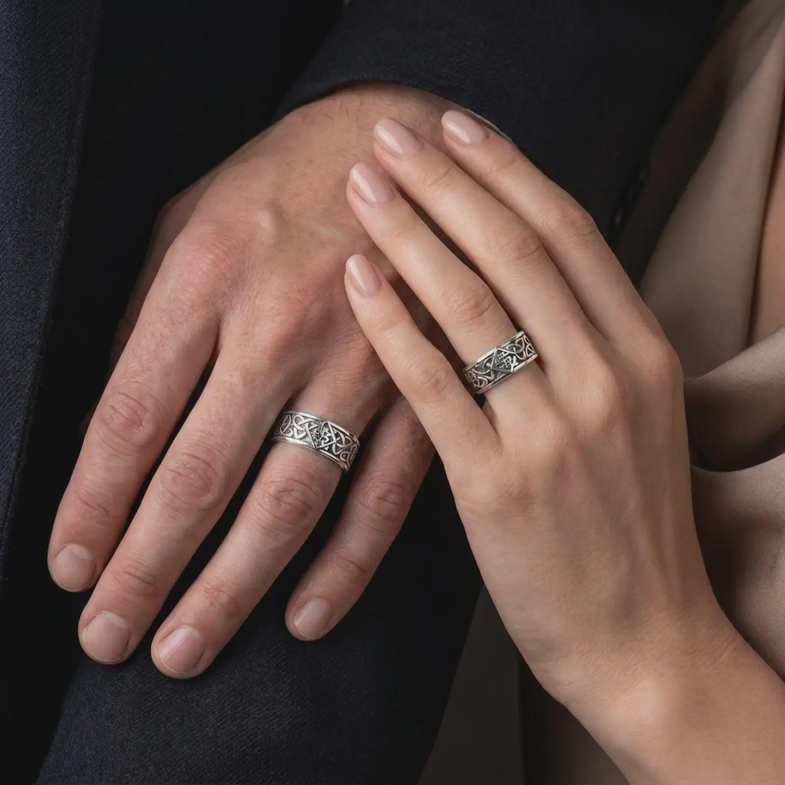 The polished silver Celtic interlace band is worn on a man’s finger, showing the continuous knotwork pattern and substantial everyday ring design in a premium lifestyle photograph.