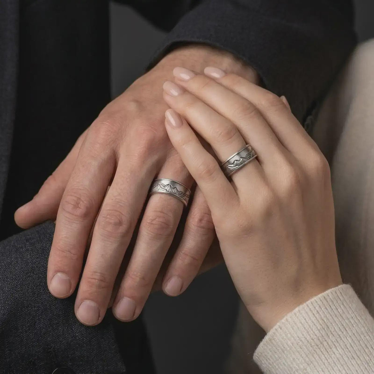 An oxidized sterling silver Grand Teton mountain ring is worn on a hand, showing the engraved mountain design and spinning fidget band style in a natural lifestyle close-up.