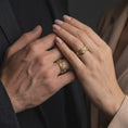 Load image into Gallery viewer, A gold plated spring flower spinner ring is worn on a finger, highlighting the botanical relief, ornamental band texture, and meaningful meditation ring style in a refined close-up lifestyle shot.
