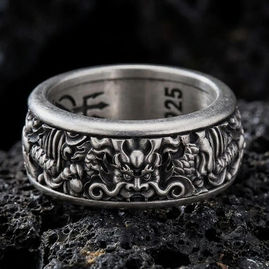 An oxidized sterling silver Asian serpent dragon spinner ring rests on dark volcanic rock, showcasing detailed dragon relief, mystical symbolism, and a wide fidget band in a dramatic macro studio close-up.