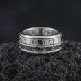 Load image into Gallery viewer, A polished silver plate pattern spinner ring is displayed on black volcanic rock, emphasizing the clean geometric sections, smooth band edges, and refined rotating construction in a detailed product photograph.
