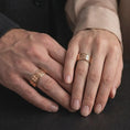 Load image into Gallery viewer, A rose gold plated plate pattern spinner ring is worn on a human hand, showcasing the textured geometric surface, elegant rotating band structure, and contemporary jewelry appeal in a premium lifestyle photograph.
