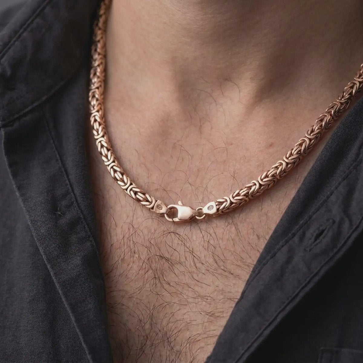 The rose gold plated Byzantine necklace is worn naturally on a man’s chest, showcasing the dimensional round links, flexible structure, and bold masculine jewelry style.