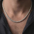 Load image into Gallery viewer, The polished silver 5mm square Byzantine necklace is worn on a man’s chest, showing the balanced chain width, woven link pattern, and refined everyday jewelry style in a premium lifestyle photograph.
