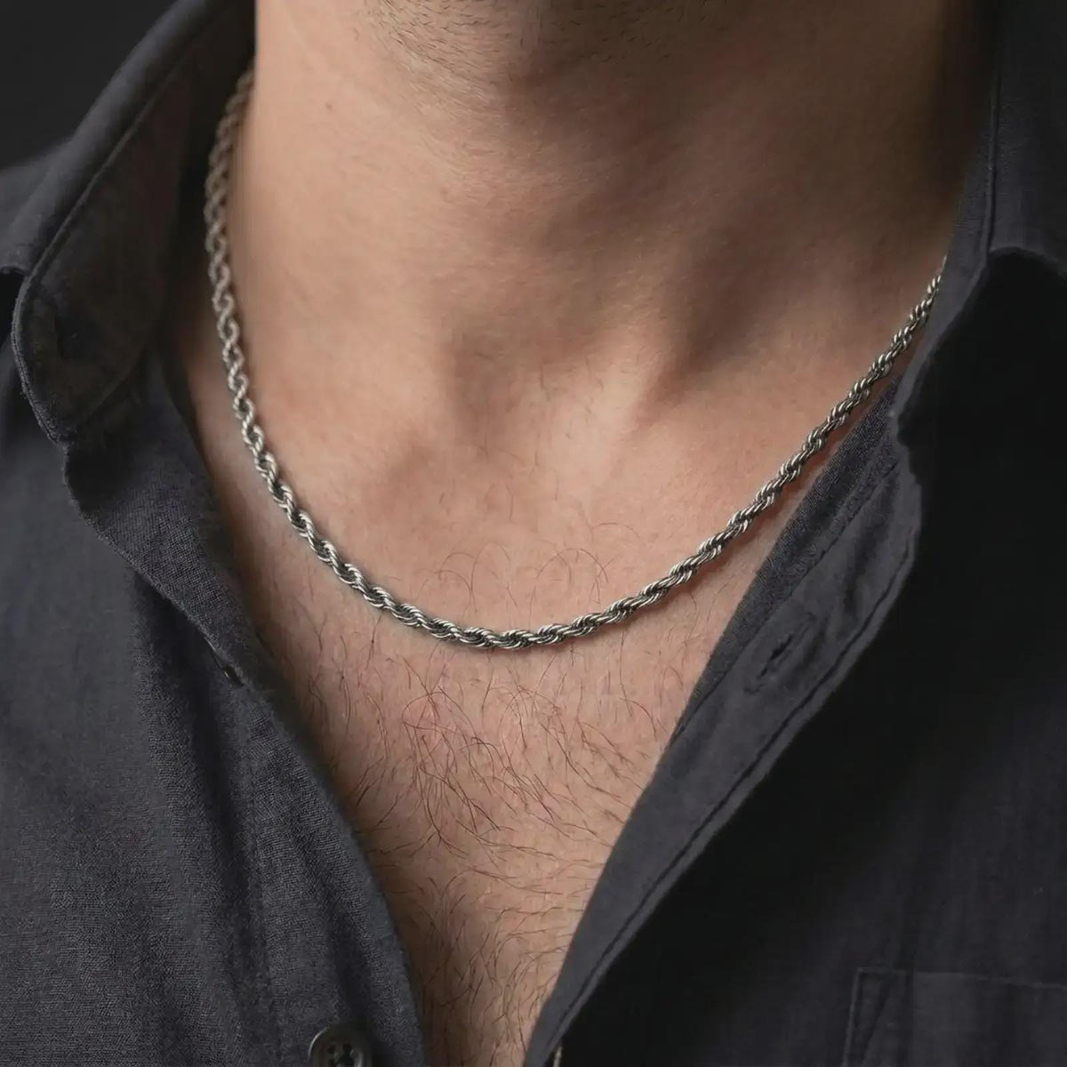 A 3mm rope chain necklace with an oxidized finish is worn on a man’s neck, displaying dark recessed twist details and a clean masculine silhouette in a close-up lifestyle shot.