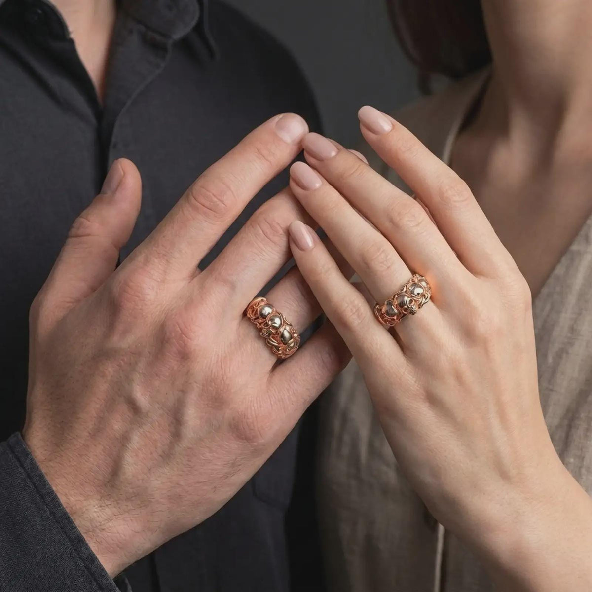 The rose gold plated skull rose band ring is worn on a finger, showcasing the three-dimensional skull, surrounding floral ornamentation, detailed relief, and bold dark romantic jewelry aesthetic.