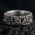 Load image into Gallery viewer, An oxidized sterling silver Asian dragon ring rests on dark volcanic rock, featuring a sculpted dragon face, curling whiskers, ornate scales, and deep recessed details in a dramatic macro studio close-up.
