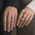 Load image into Gallery viewer, An oxidized sterling silver Byzantine chain ring is worn on a finger, displaying the dark recessed details, raised woven links, and bold unisex band profile in a close-up lifestyle shot.
