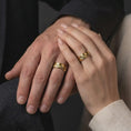 Load image into Gallery viewer, A gold plated Grand Teton mountain ring is worn naturally on a hand, displaying the detailed mountain landscape and elegant spinning band form in a close-up lifestyle image.
