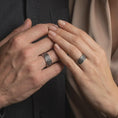 Load image into Gallery viewer, An oxidized sterling silver Celtic knot spinner ring is worn on a hand in a lifestyle composition, showing the intricate Irish knot pattern and bold unisex wedding band style.
