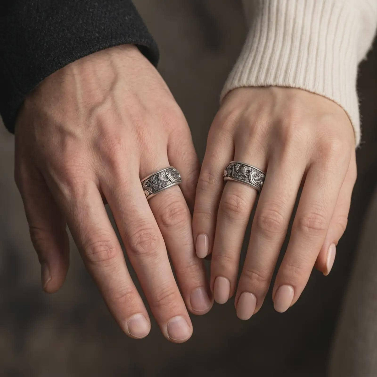 An oxidized koi fish spinner ring is worn on a finger, displaying the dark recessed wave details, raised sterling silver carp motifs, and calming wide band profile in a close-up lifestyle shot.