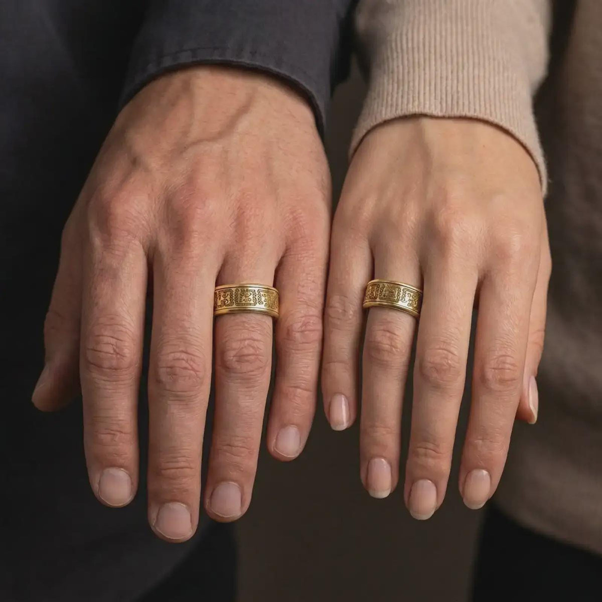 A gold plated Aztec spinner ring is worn on a finger, highlighting the symbolic engraved pattern, wide wedding band form, and personalizable jewelry design in a refined close-up lifestyle shot.