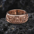 Load image into Gallery viewer, The rose gold plated serpent dragon spinner ring is arranged on black volcanic rock, emphasizing the mystical dragon relief, rich carved texture, and elegant fidget band design in a detailed macro image.
