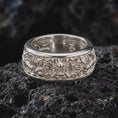 Load image into Gallery viewer, The polished silver dragon spinner ring is displayed on textured black volcanic rock, highlighting the intricate Asian serpent design, sculpted details, and smooth spinning band profile in a premium macro photograph.

