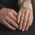 Load image into Gallery viewer, A gold plated geometric spinner ring is worn on a human hand, emphasizing the segmented plate motif, warm gold tone, and distinctive statement band design in a close-up lifestyle shot.
