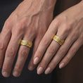Load image into Gallery viewer, A gold plated Baroque wedding ring is worn on a finger, highlighting the raised fleur-de-lis design, scrolling ornamentation, and distinctive alternative wedding band profile in a refined close-up lifestyle image.
