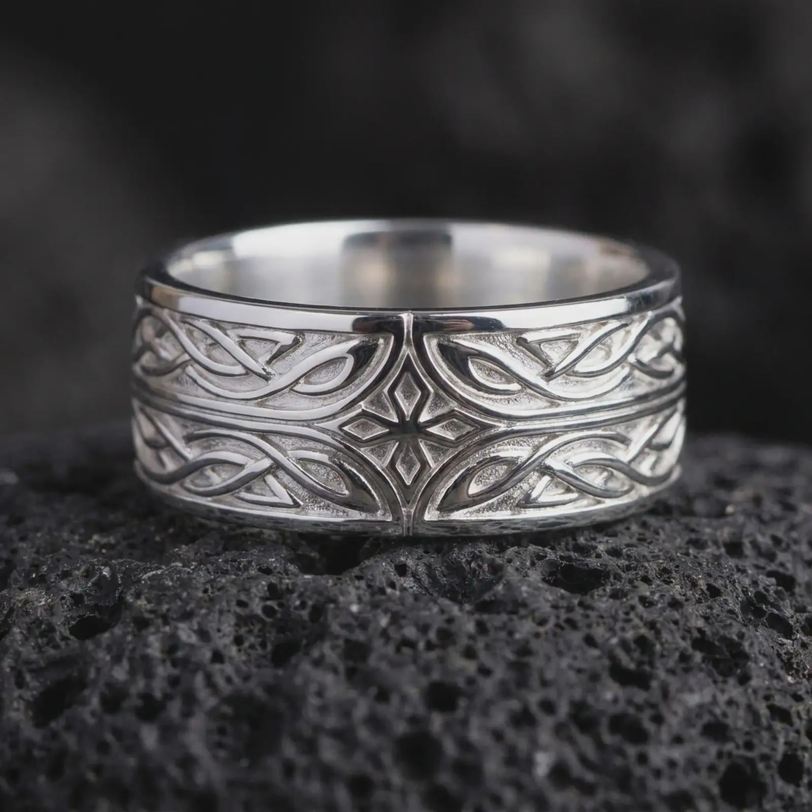 The polished silver Elven fantasy ring is displayed on textured black volcanic rock, highlighting the raised star motif, elegant interlace pattern, smooth edges, and wide sterling silver band in a premium macro photograph.