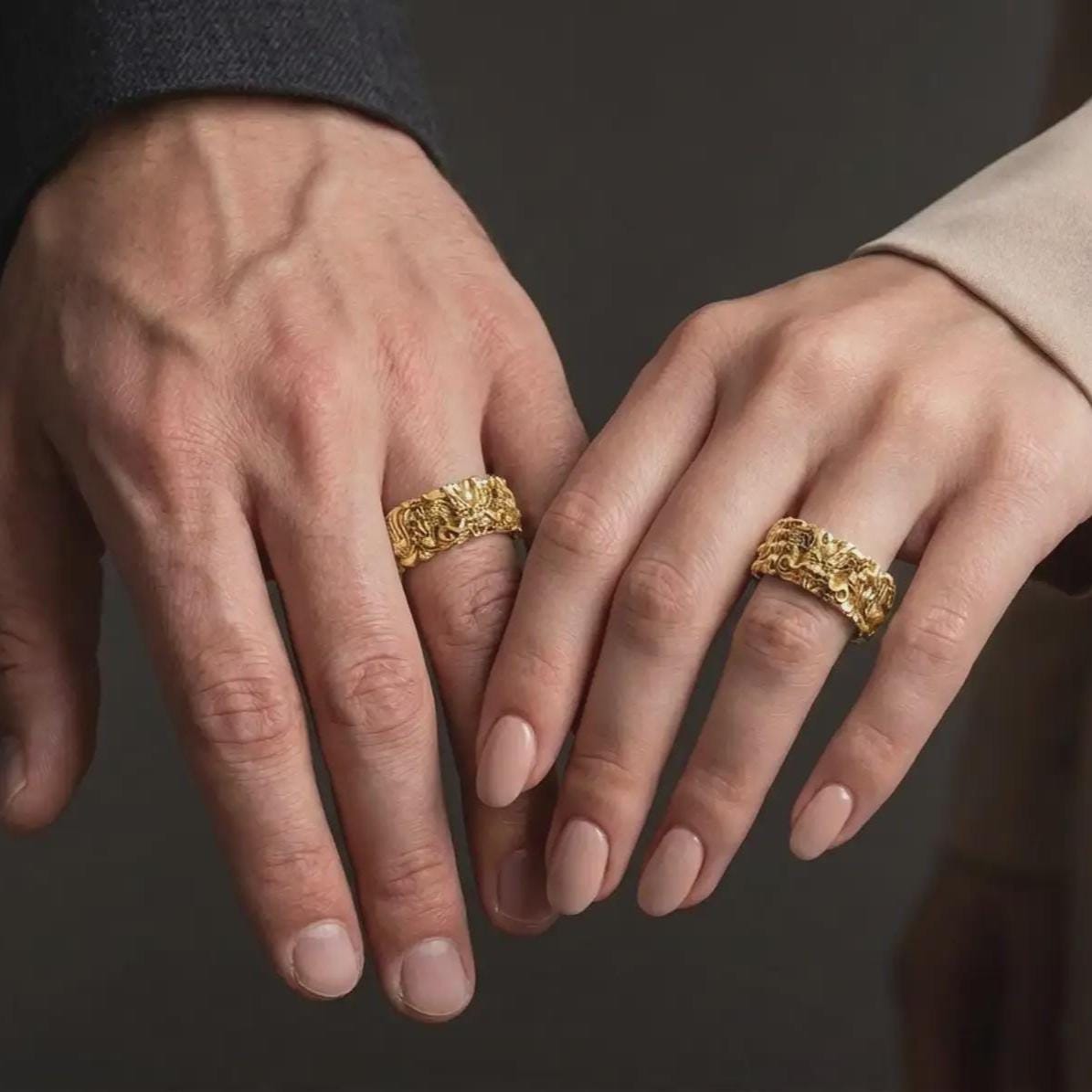 A gold plated mythical dragon ring is worn on a finger, highlighting the raised Asian-inspired dragon face, intricate scale pattern, and bold symbolic wedding band design in a refined close-up lifestyle shot.