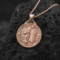 Load image into Gallery viewer, The rose gold plated crusader pendant is arranged on black volcanic rock, emphasizing the armored knight, sword, Christian cross shield, architectural details, and bold medieval medallion design in a refined macro image.
