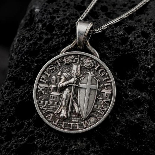 An oxidized sterling silver Templar Knight pendant rests on dark volcanic rock, featuring an armored medieval warrior with a sword, cross shield, castle backdrop, and detailed round medallion border in a macro studio close-up.