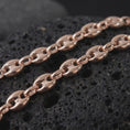Load image into Gallery viewer, The rose gold plated 11mm Mariner necklace is arranged on black volcanic rock, emphasizing its broad oval links, central bars, smooth dimensional surfaces, and bold nautical-inspired chain profile in a detailed macro image.
