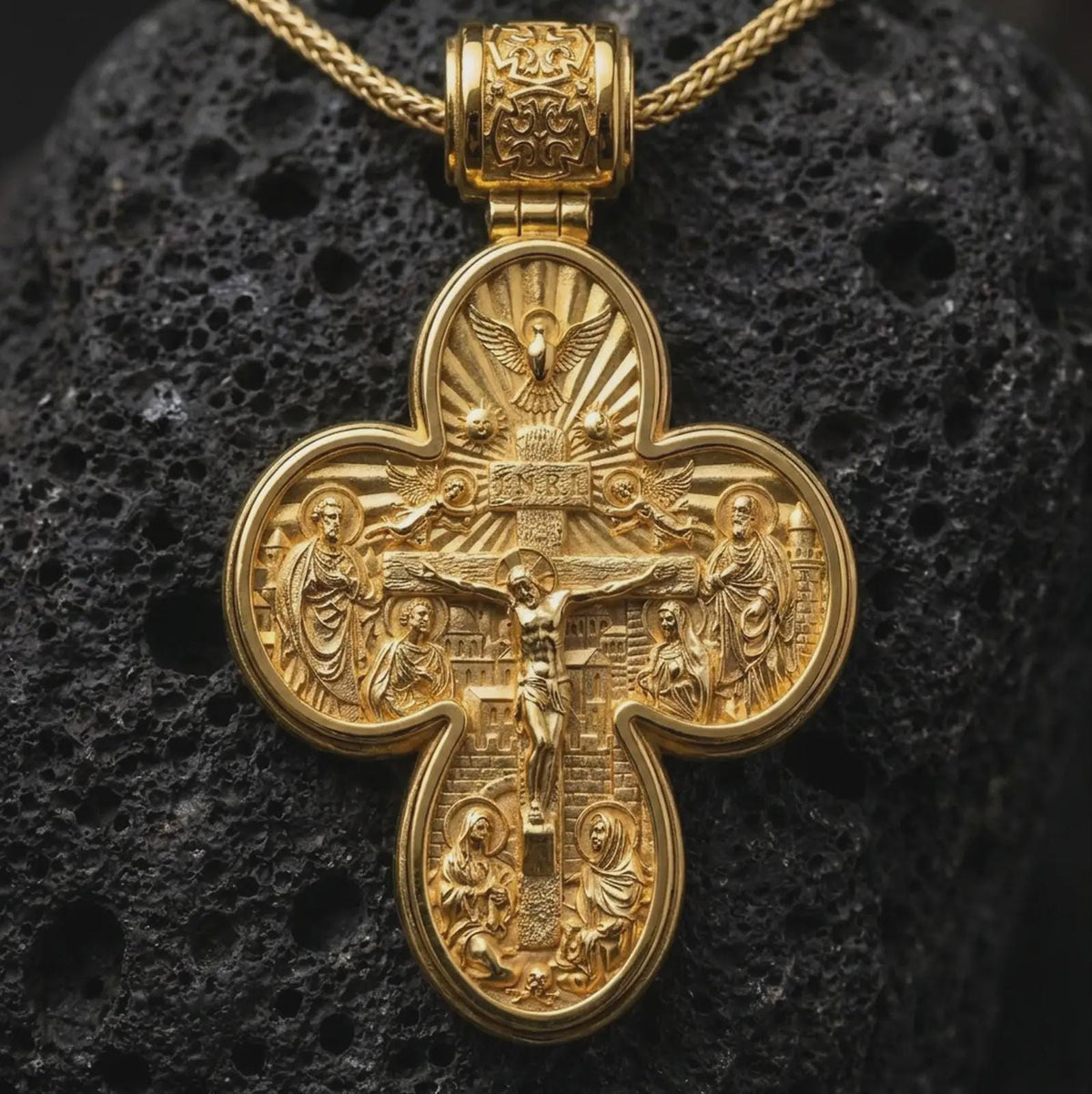 A gold plated Saint Michael protection pendant rests on rugged volcanic rock, featuring the ornate cross silhouette, devotional scene, and symbolic double sided Christian design in a luxury macro studio close-up.