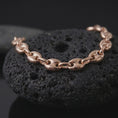 Load image into Gallery viewer, The rose gold plated Mariner bracelet is arranged on black volcanic rock, emphasizing its rounded puffed links, classic anchor chain structure, and bold 11mm statement profile in a detailed macro image.
