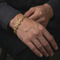 Load image into Gallery viewer, A gold plated 11mm Mariner bracelet is worn around a man's wrist, highlighting the broad anchor links, dimensional construction, and confident men's statement jewelry style in a refined close-up lifestyle shot.
