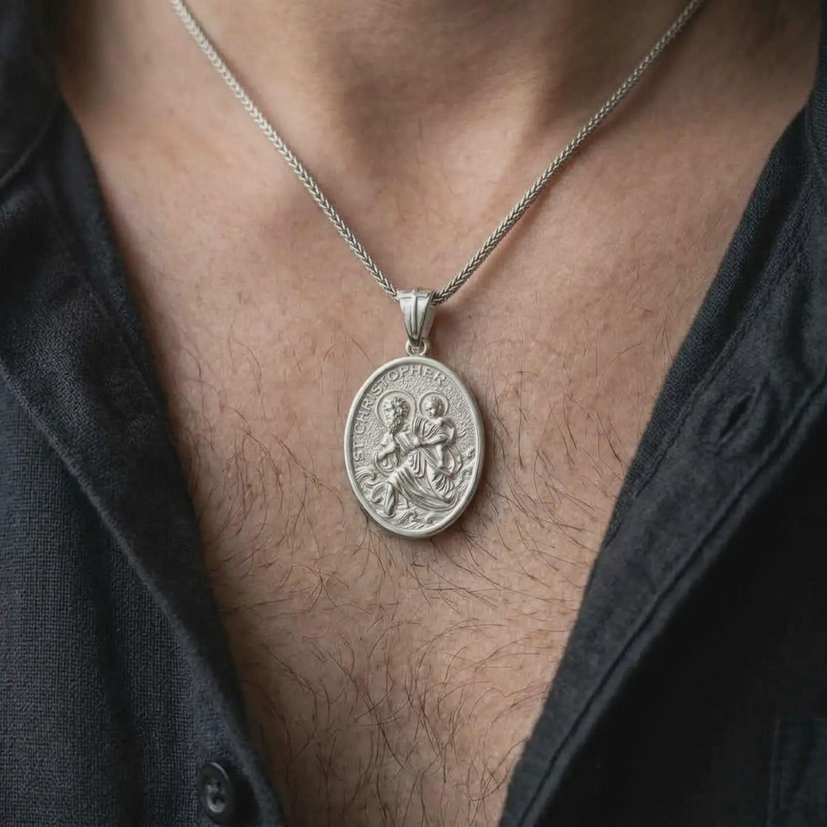 The polished silver St. Christopher necklace is worn naturally on the chest, showing the detailed patron saint of travelers image, Christ Child, haloed figures, and elegant sterling silver medallion profile in a premium lifestyle photograph.