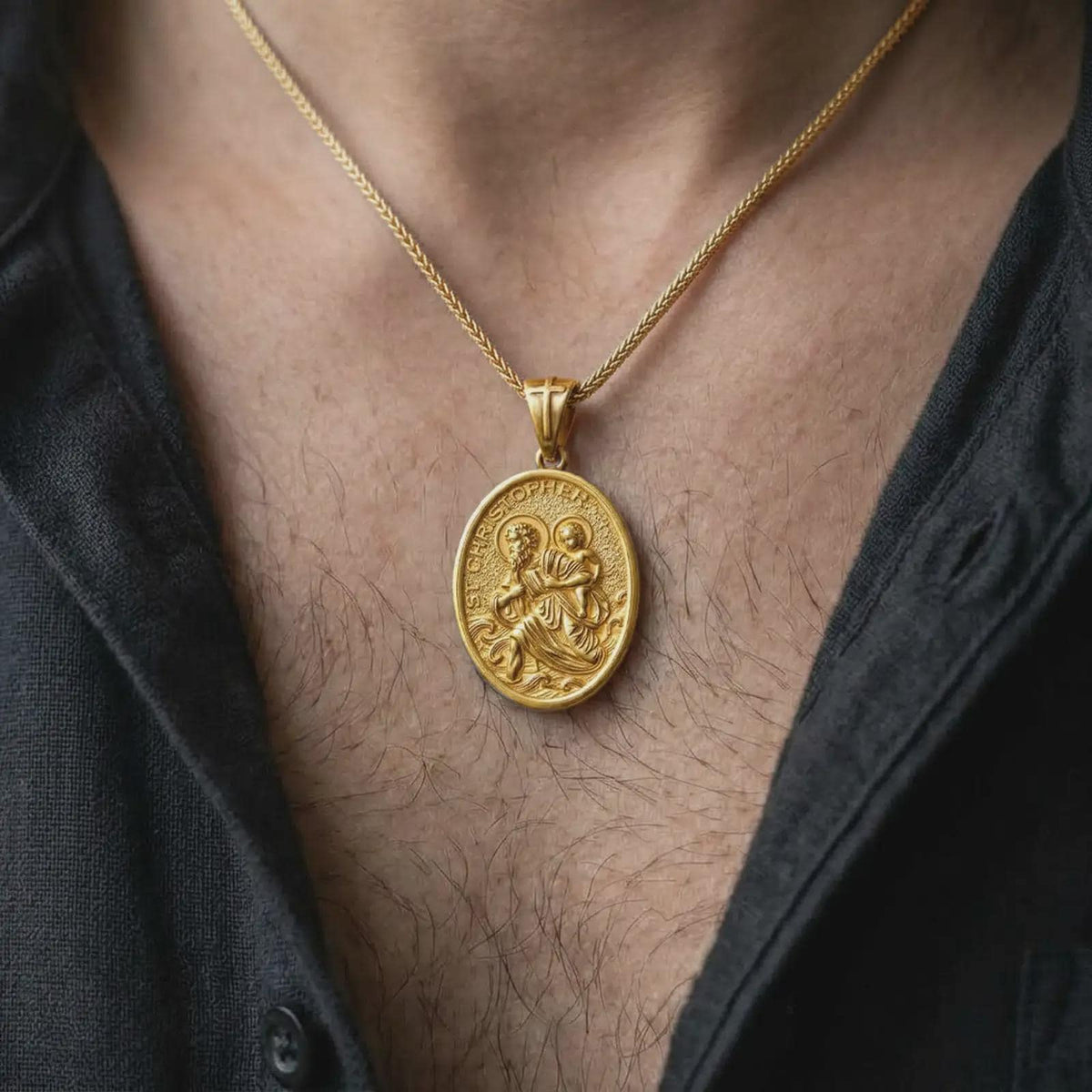 A gold plated St. Christopher travelers medal is worn on the chest, highlighting the saint carrying the Christ Child, symbolic wave details, and meaningful Catholic protection necklace design in a refined lifestyle shot.