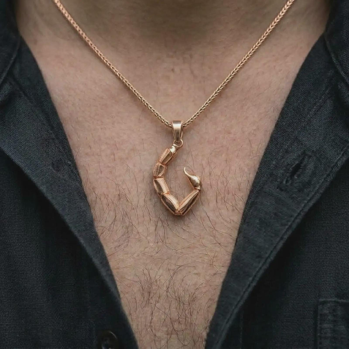 The rose gold plated scorpion tail necklace is worn on the chest, showcasing the segmented construction, pointed stinger, compact statement profile, and bold symbolic zodiac jewelry design.