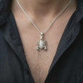 Load image into Gallery viewer, An polished silver Scorpio pendant is worn naturally on the chest, displaying the detailed scorpion anatomy, and bold animal totem profile in a close-up lifestyle image.

