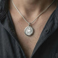 Load image into Gallery viewer, The polished silver RPG pendant is worn naturally on the chest, showing the raised merchant emblem, decorative circular border, smooth silver highlights, and unisex fantasy necklace design.
