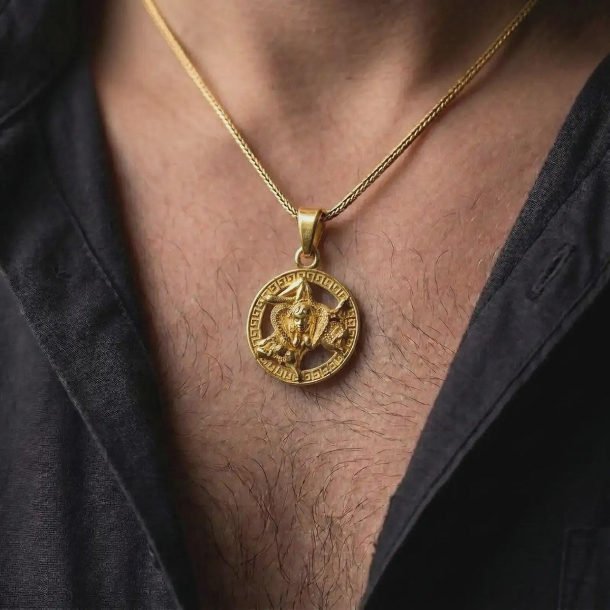 Gold plated Trinacria necklace worn on the chest, displaying the iconic Sicilian three-legged symbol, Medusa centerpiece, and Greek key medallion frame.