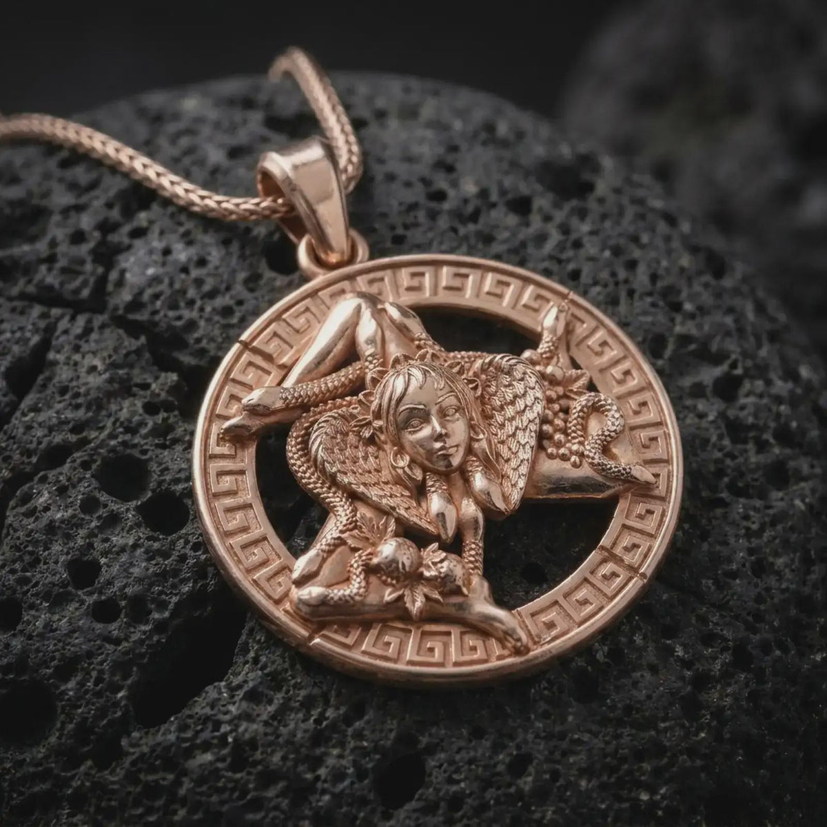 Rose gold plated Sicilian Trinacria necklace on black volcanic stone, highlighting the Medusa center, three-legged Sicily symbol, and detailed circular medallion design.