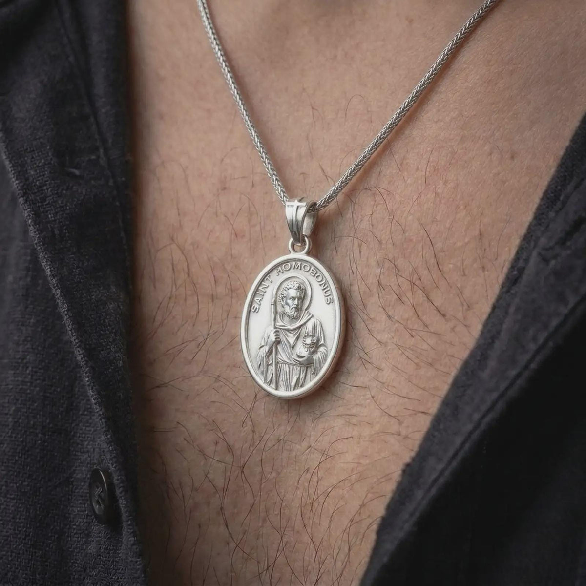 Polished silver Saint Homobonus pendant worn on the chest, featuring the patron saint medal in a classic oval design for business owners, merchants, and Catholic professionals.