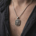 Load image into Gallery viewer, Oxidized sterling silver Tlaloc necklace worn on the chest, displaying the recognizable rain god mask, goggle eyes, fangs, and detailed Mexica ceremonial design.
