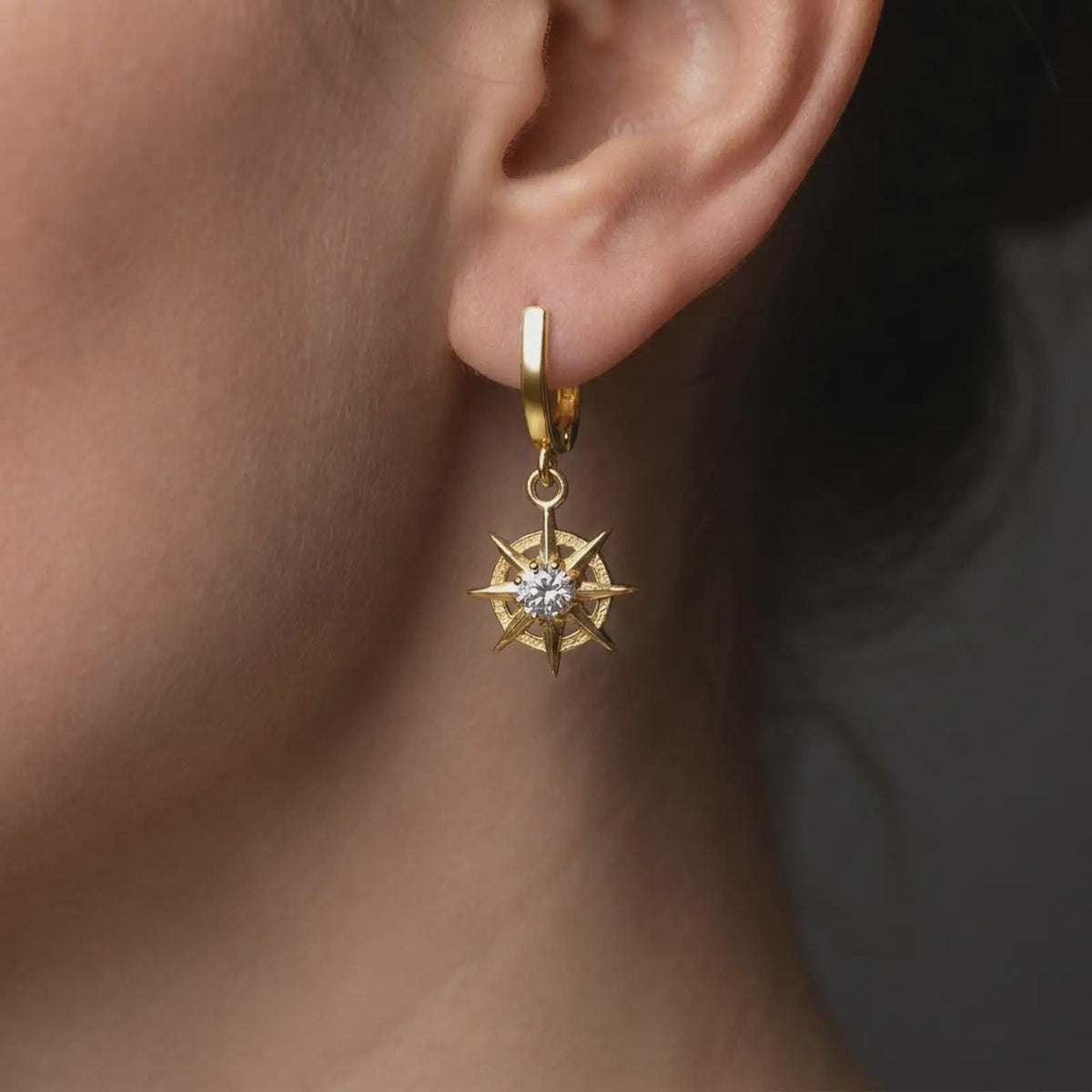 Gold plated finish over sterling silver Gale inspired single earring worn on the ear, featuring an eight-point starburst charm with a clear faceted center stone, inspired by Baldur’s Gate 3 wizard jewelry.