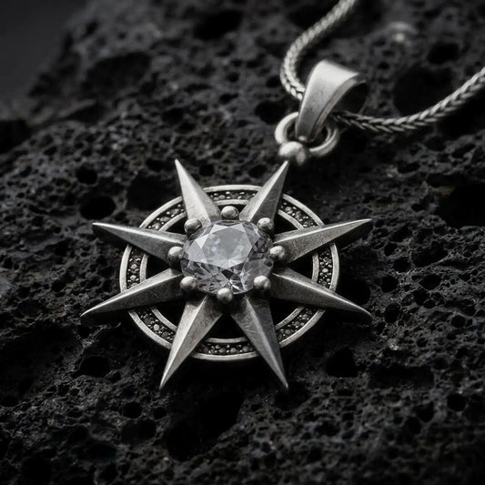 Oxidized sterling silver Gale's Earring inspired pendant on black volcanic rock, featuring an eight-point starburst design and a large clear faceted center stone.