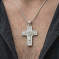 Load image into Gallery viewer, The polished silver Good Shepherd necklace is worn naturally on the chest, showing the detailed shepherd figure, sheep, dove symbol, smooth cross outline, and meaningful Catholic jewelry style in a premium lifestyle photograph.
