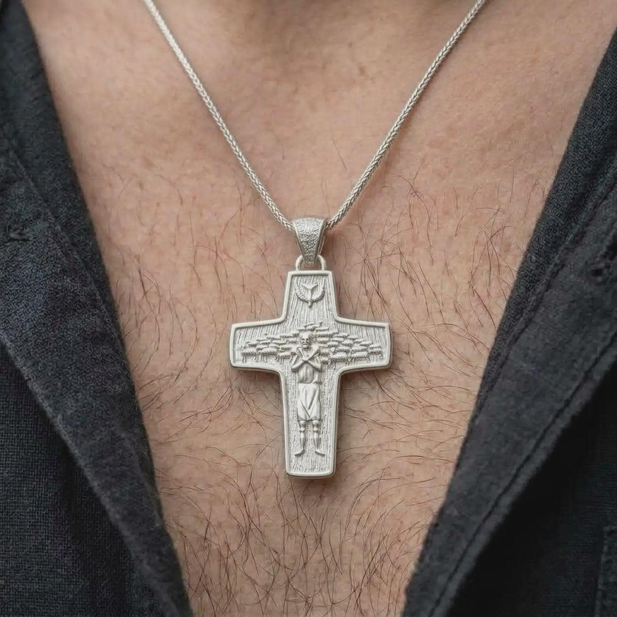 The polished silver Good Shepherd necklace is worn naturally on the chest, showing the detailed shepherd figure, sheep, dove symbol, smooth cross outline, and meaningful Catholic jewelry style in a premium lifestyle photograph.