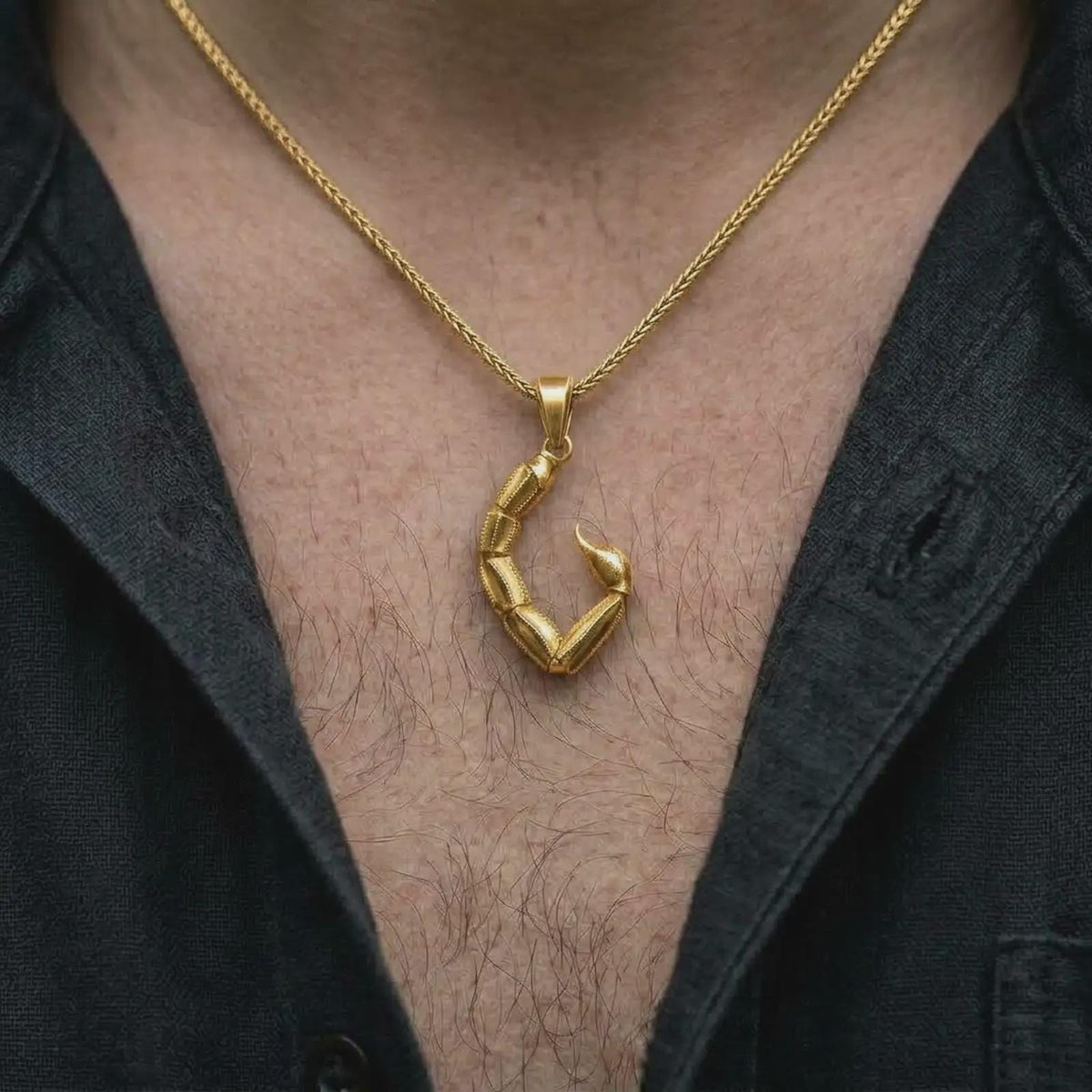 A gold plated Scorpio tail pendant is worn on the chest, highlighting the sculptural armor-like segments, raised details, curved stinger, and powerful astrology-inspired jewelry style in a refined lifestyle shot.
