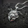 Load image into Gallery viewer, The polished sterling silver insect pendant is displayed on black volcanic rock, highlighting the reflective ant head, textured eyes, articulated antennae, and dimensional pincer-like mandibles in a premium macro photograph.
