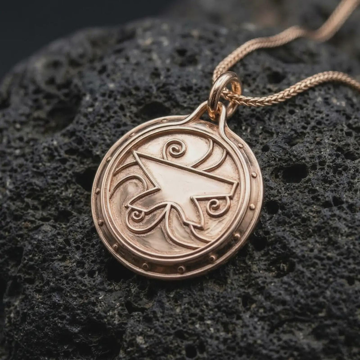 The rose gold plated fantasy amulet is arranged on black volcanic rock, emphasizing the raised geometric emblem, flowing spiral accents, circular medallion shape, and detailed RPG-inspired design.