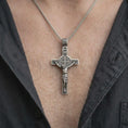 Load image into Gallery viewer, An oxidized sterling silver Saint Benedict crucifix necklace is worn on the chest, displaying the Jesus figure, INRI inscription, detailed medal center, and traditional Catholic devotional style.
