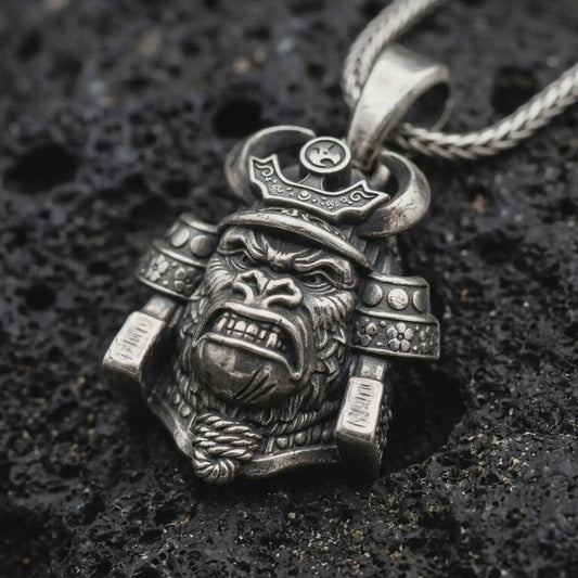 An oxidized sterling silver King Gorilla Samurai pendant rests on black volcanic rock, featuring a fierce gorilla face, curved helmet horns, decorative crown, and detailed Japanese warrior armor.