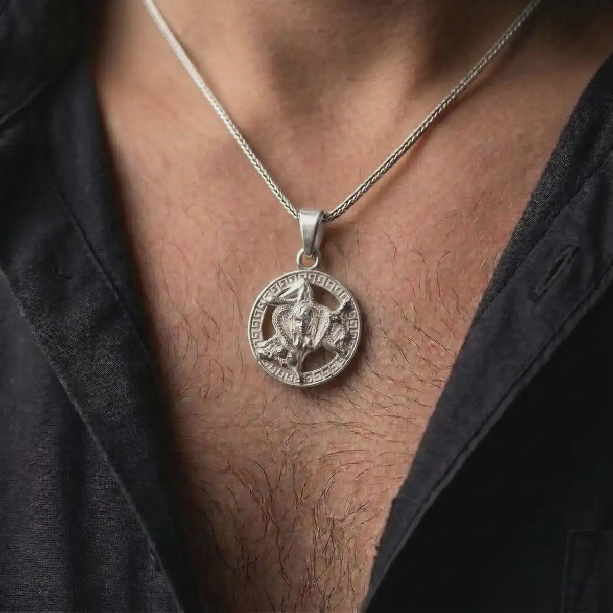 Polished silver Sicilian Triskelion pendant worn on the chest, featuring the traditional Trinacria symbol of Sicily with detailed Medusa relief and circular border.