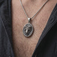 Load image into Gallery viewer, Oxidized sterling silver Aries necklace worn on the chest, showing the dimensional ram head, large curved horns, textured medallion, and bold zodiac jewelry design.
